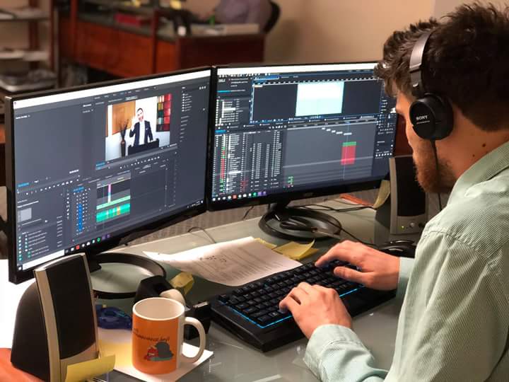 Image of a man editing a video on a PC with two monitors