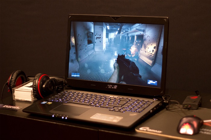 Image of an Asus gaming laptop open on a desk and playing an FPS game