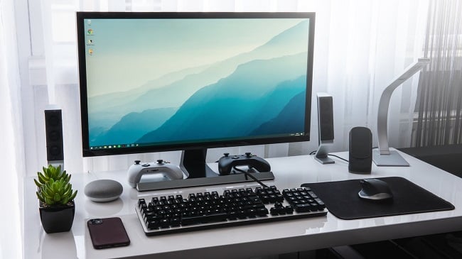 Image of a clean and minimal computer desk setup in front of a bright window