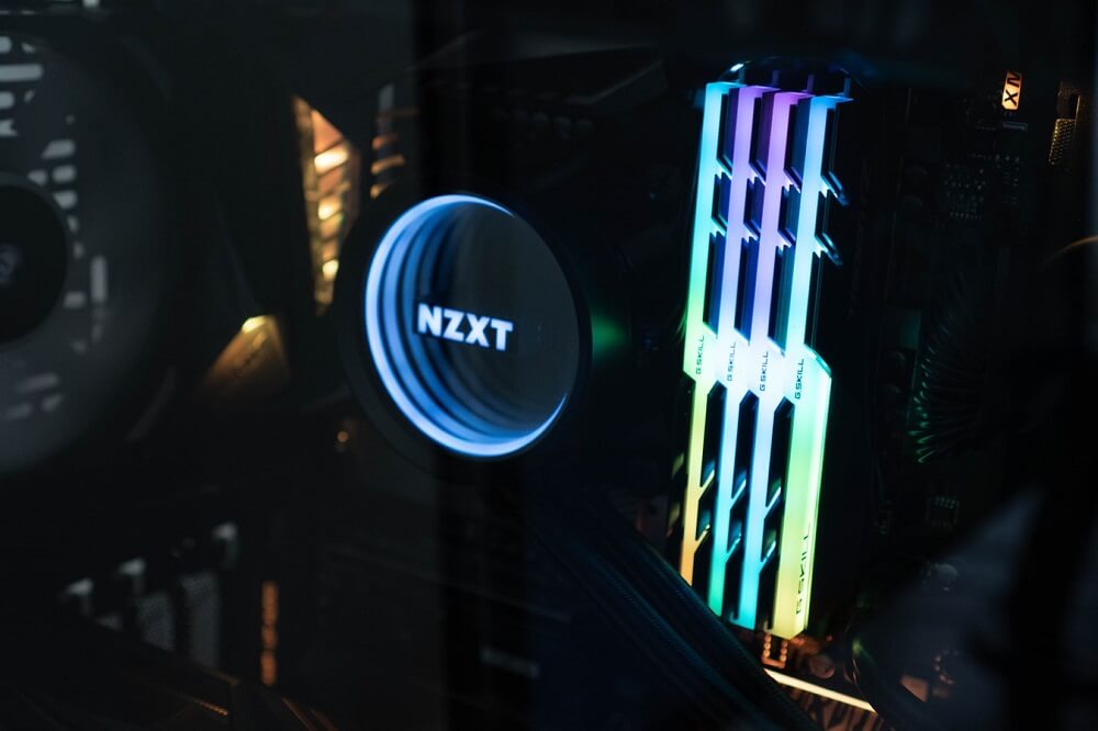 Close up of 4 lit up sticks of RGB G-Skill RAM in a motherboard next to an NZXT CPU cooler